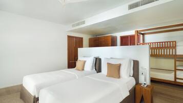 Een hotelkamer met twee bedden, een plafondventilator, houten stapelbedden en een klein nachtkastje.
