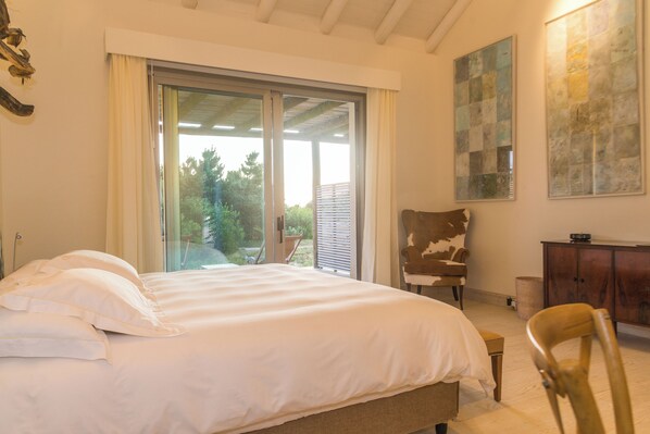 A bedroom with a large bed, a chair, a cabinet, and a painting on the wall.