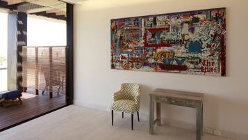 Relax in a stylish space with a large abstract painting, a patterned armchair, and a wooden table.