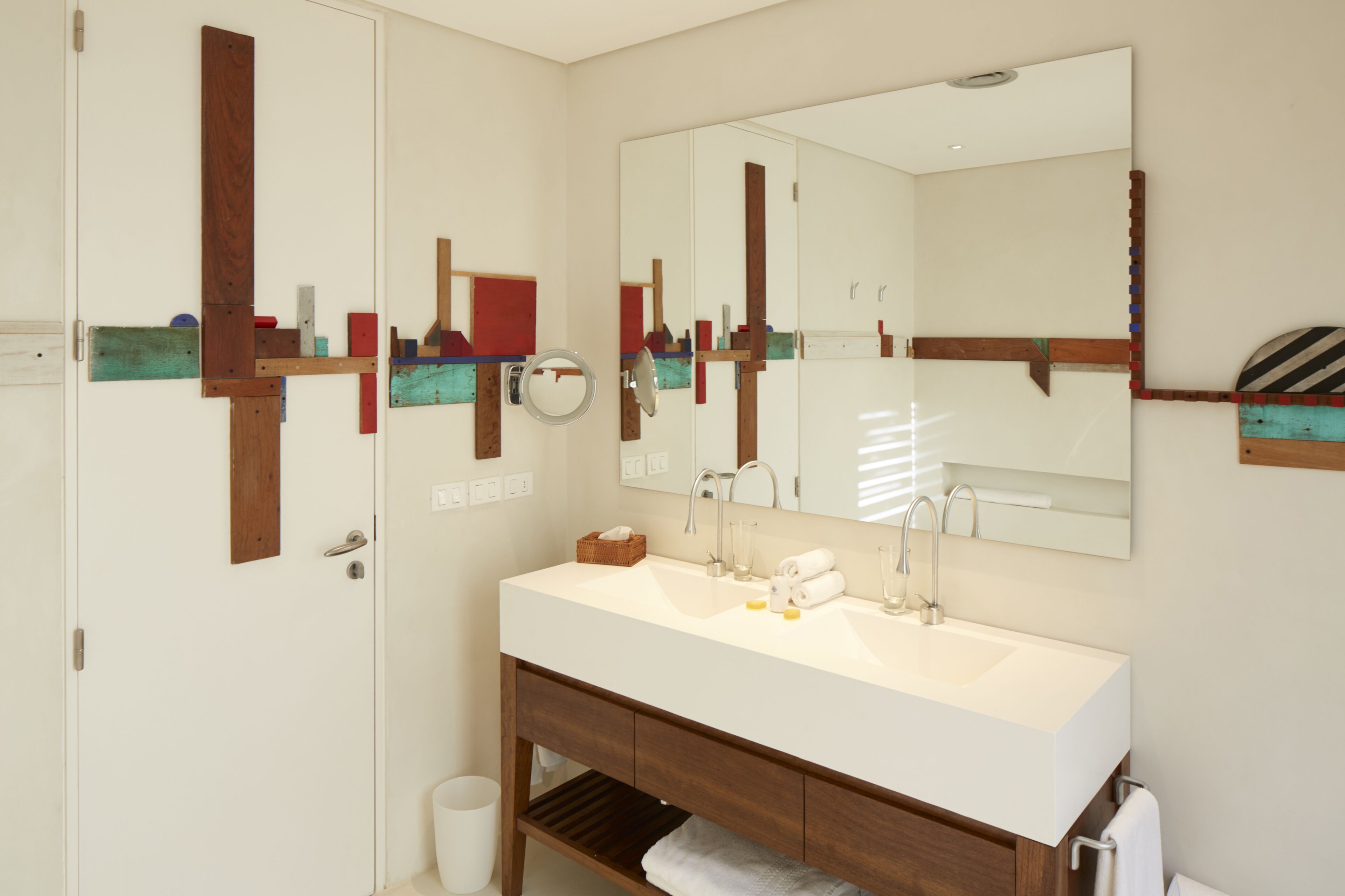 Un baño moderno con un espejo grande, dos lavamanos y detalles de madera.