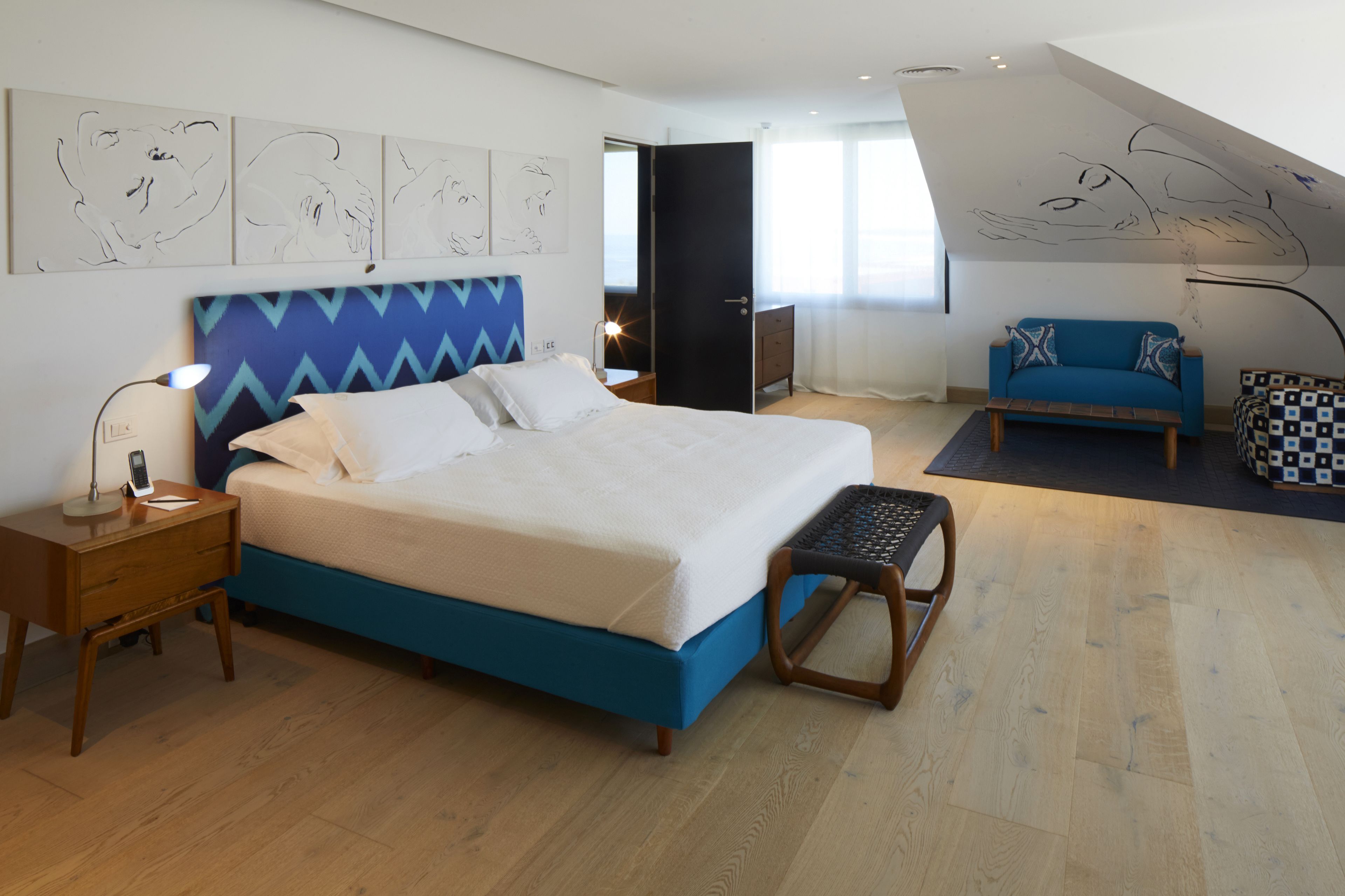 Un dormitorio moderno con una cama grande, un escritorio, una silla y un sofá.