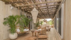 A covered outdoor area with wicker furniture, large potted plants, and a hanging light fixture. - Bahia Vik Jose Ignacio (José Ignacio)