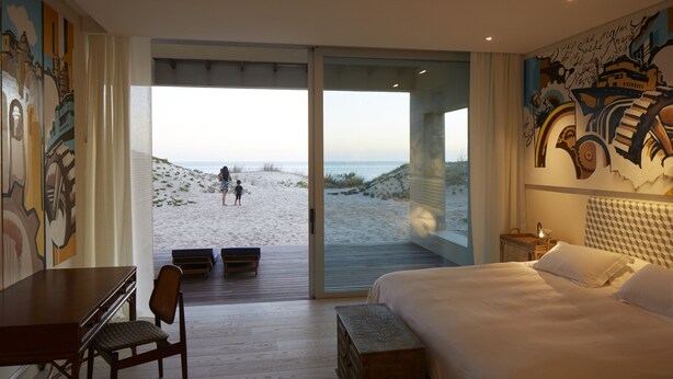 A hotel room with a large bed, a desk, a chair, and a view of the beach. - Bahia Vik Jose Ignacio (José Ignacio)