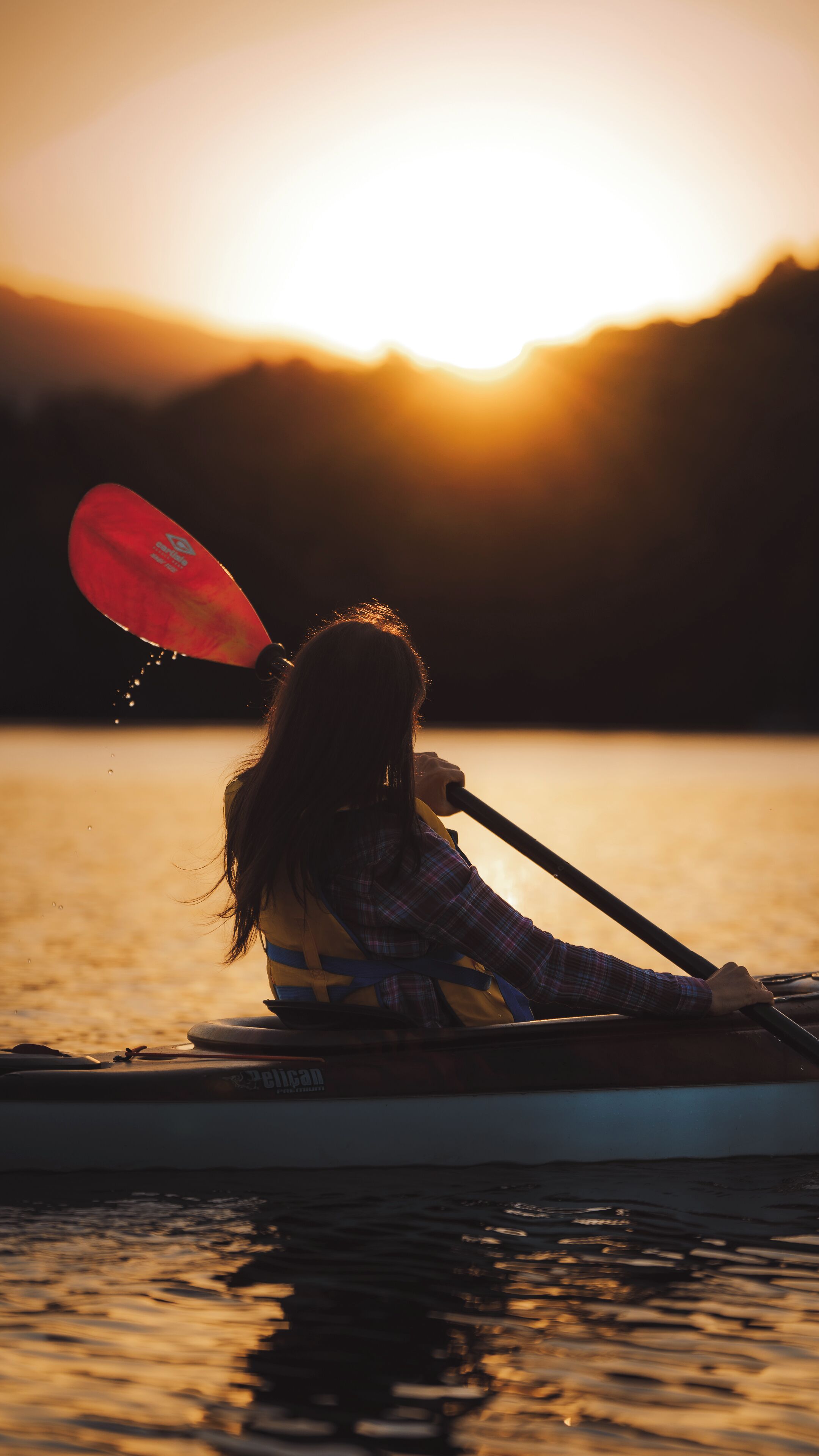 Una persona practica kayak en aguas tranquilas durante el atardecer.