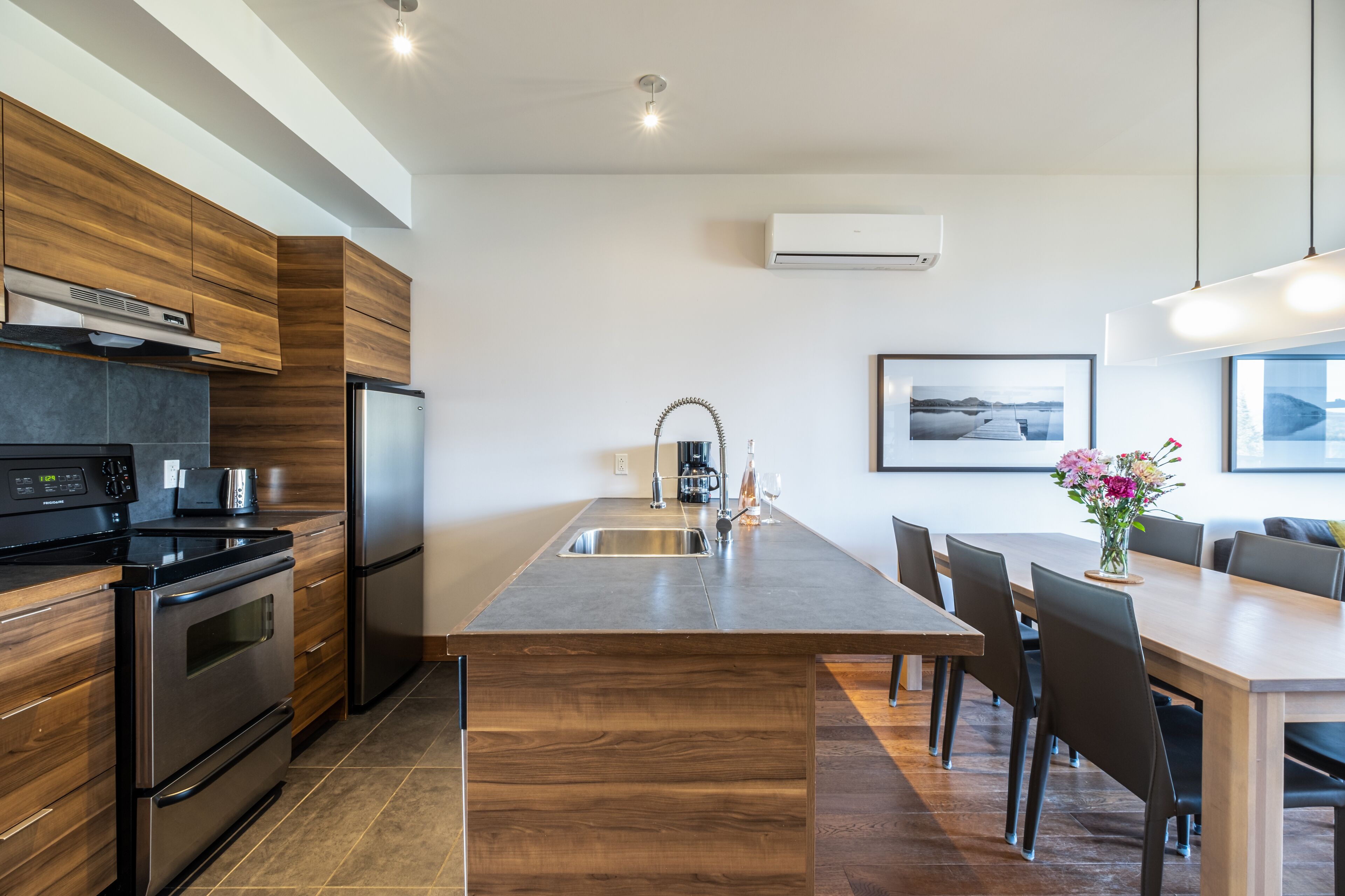 Una cocina moderna con armarios de madera, electrodomésticos de acero inoxidable y una isla central con asientos.