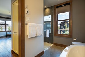 A modern bathroom with a glass shower, a large window, and a view of the mountains. - Suites Sur Lac (Lac-Superieur)
