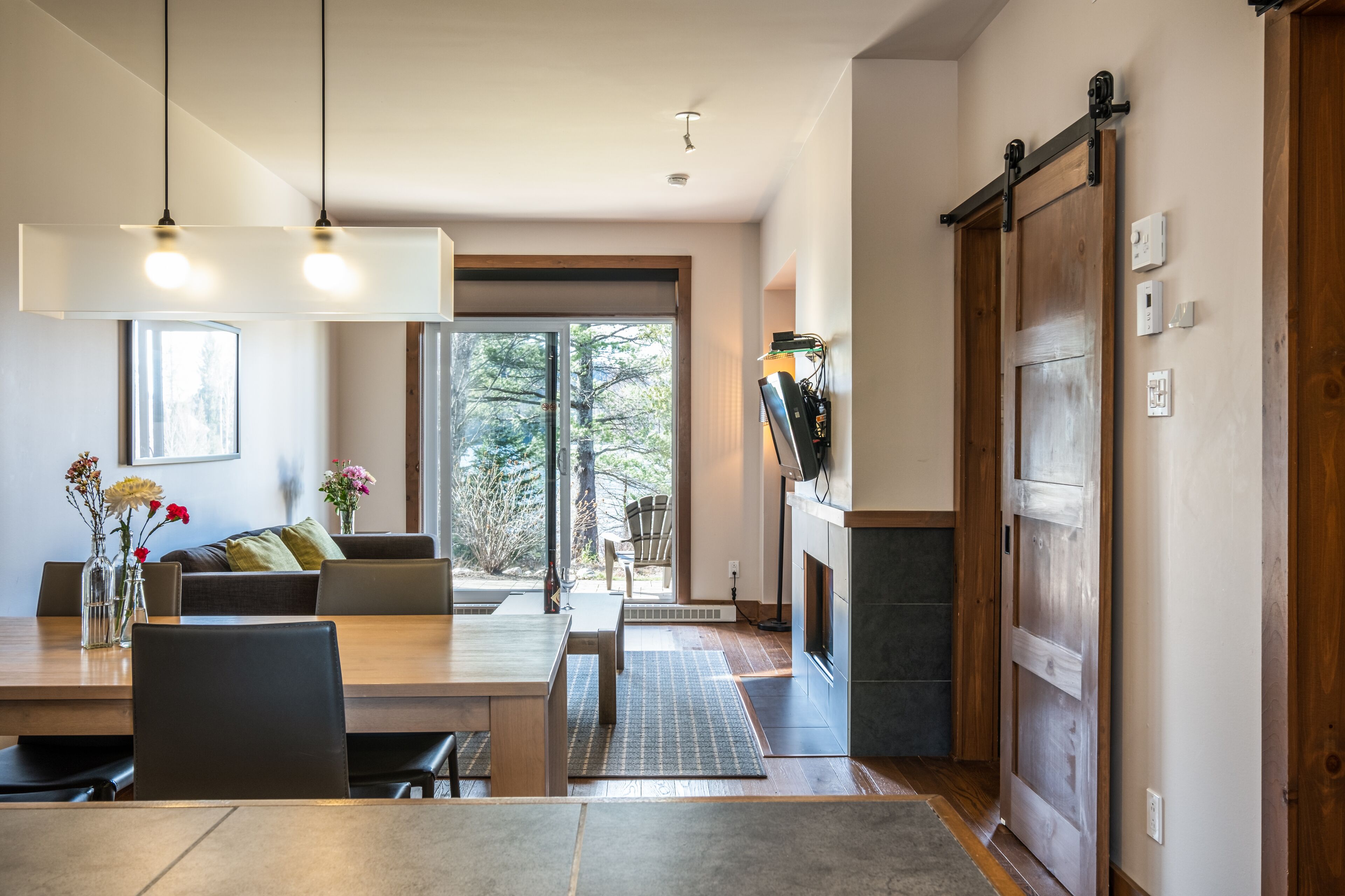 Un área de comedor moderna con una mesa y sillas de madera, un sofá y una chimenea.