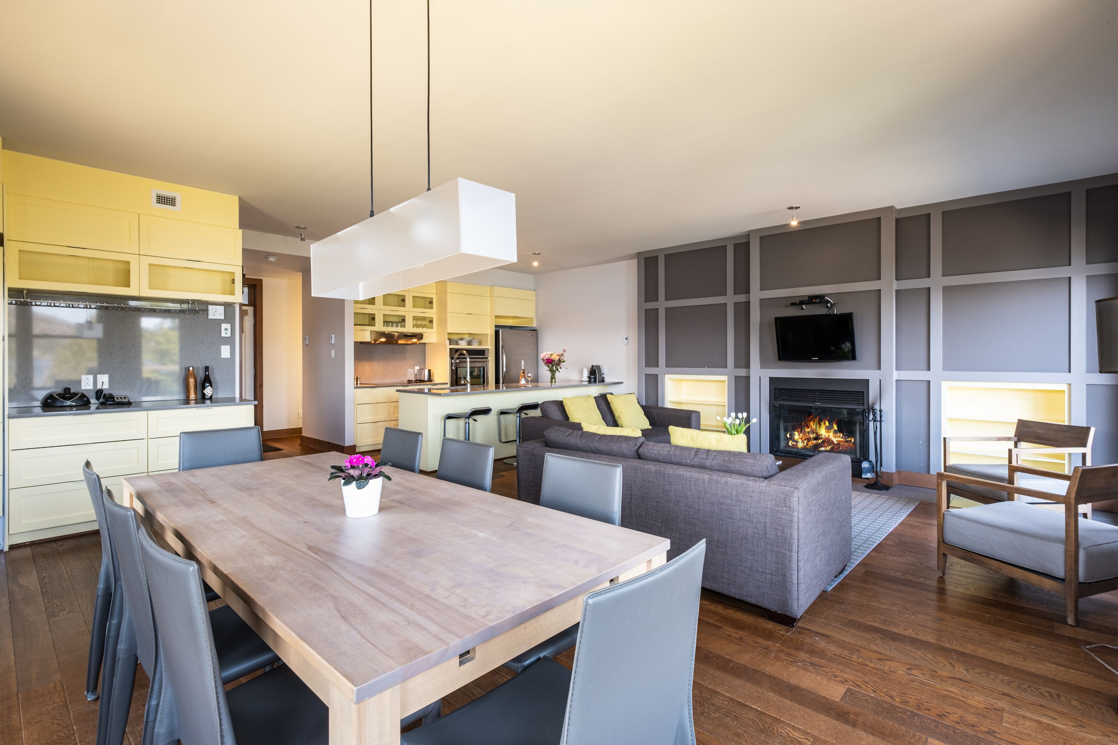 A modern living space with a dining area, kitchen, and seating area.