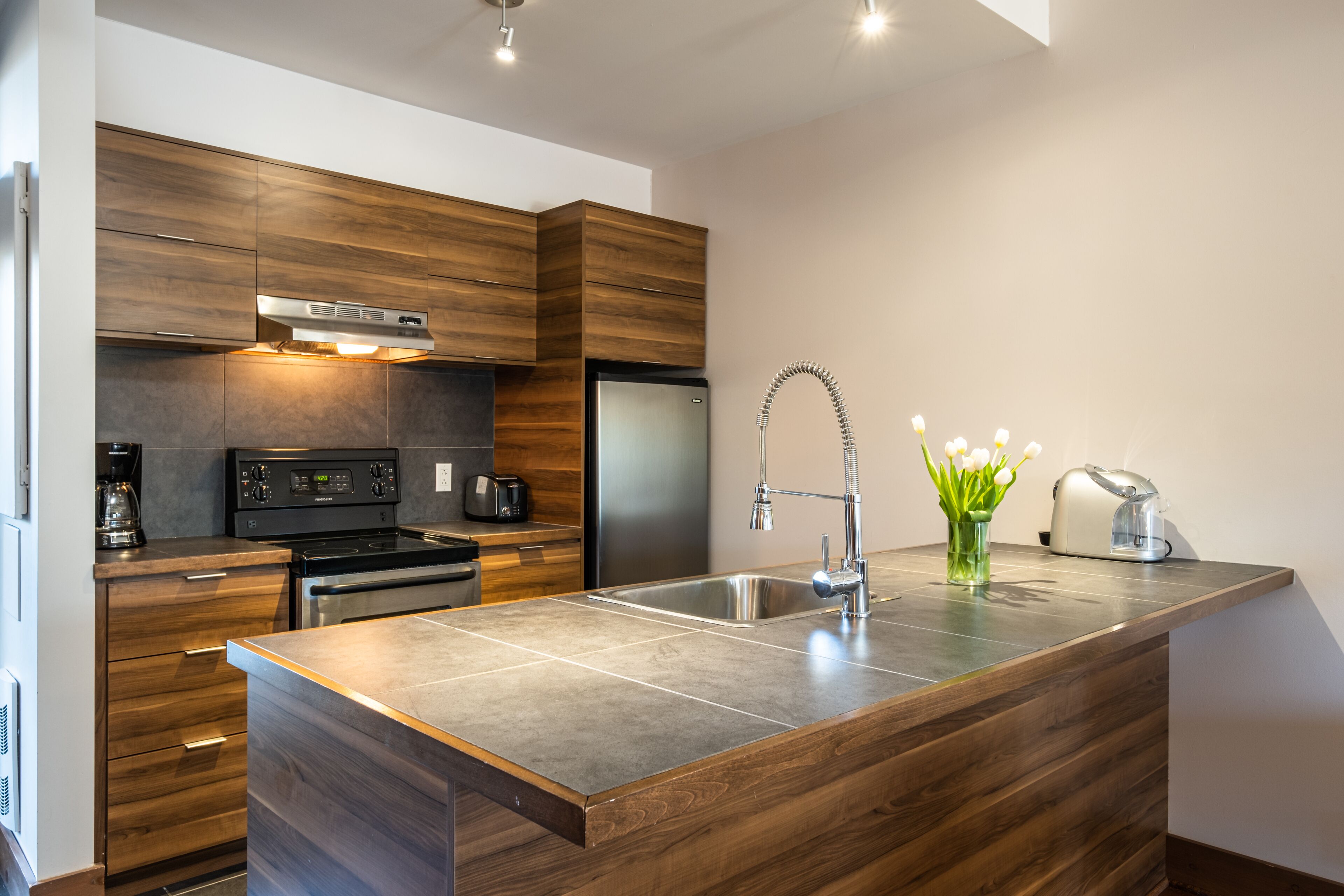 Une cuisine moderne avec des meubles en bois, un évier en acier inoxydable et un four encastré.