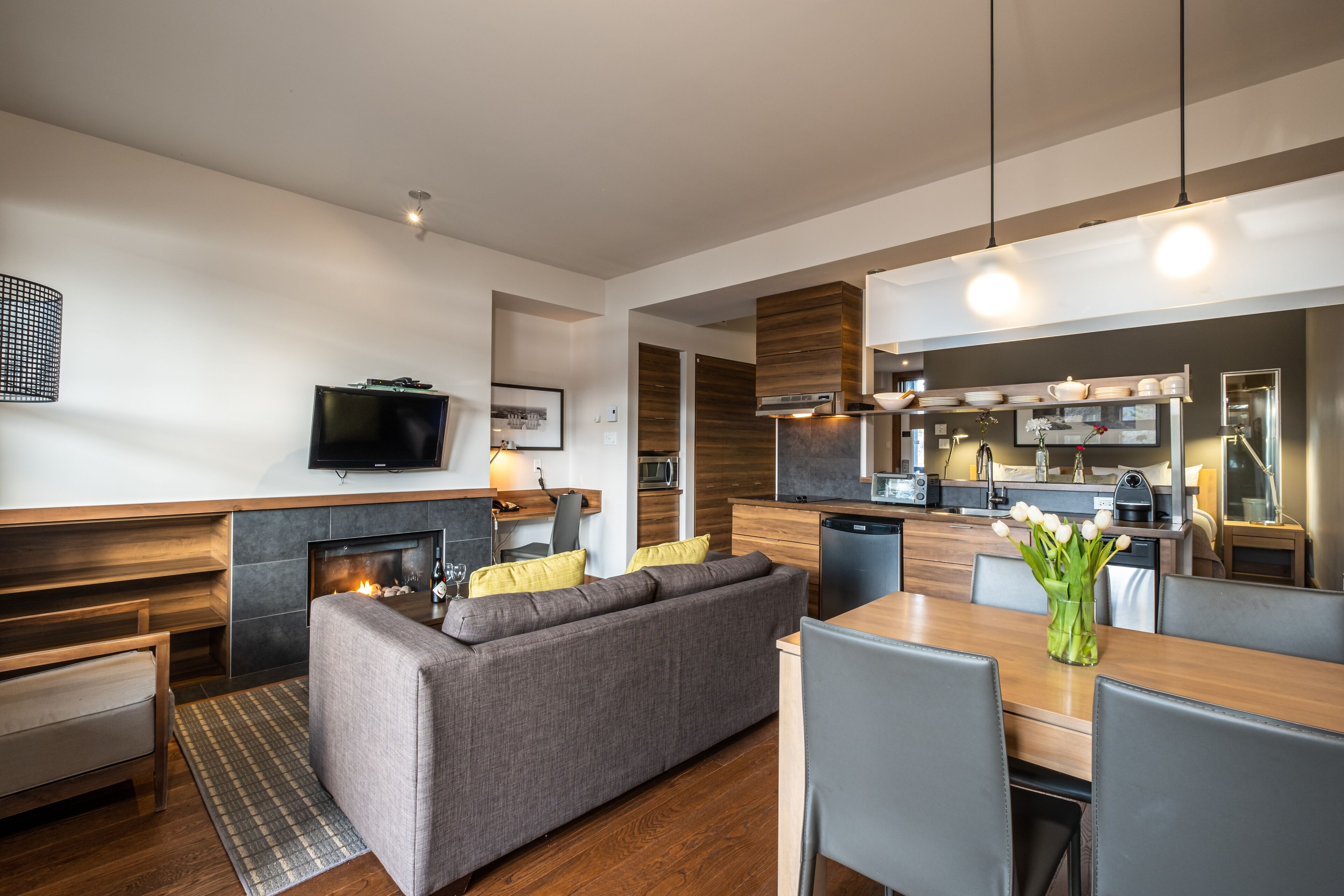A modern living room with a sofa, dining table, and kitchen area.