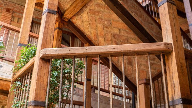 A wooden staircase with a railing, surrounded by stone walls and wooden beams. - Hotel Plaza Mayor (Villa de Leyva)