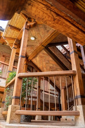 Una escalera de madera con barandilla, rodeada de muros de piedra y vigas de madera.