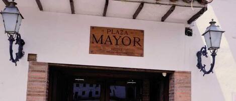 The entrance to Plaza Mayor with a sign above the door, brick steps leading up to the entrance, and two wall-mounted lanterns on either side.
