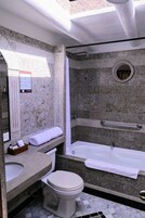 Un baño con pared de piedra, una bañera, un inodoro y un lavamanos.