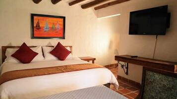 Un dormitorio con una cama, dos almohadas, un cuadro, un televisor y un escritorio.