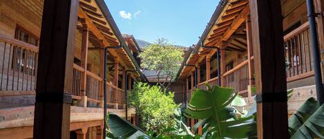 A wooden building with a central courtyard, large windows, and a tree in the middle.