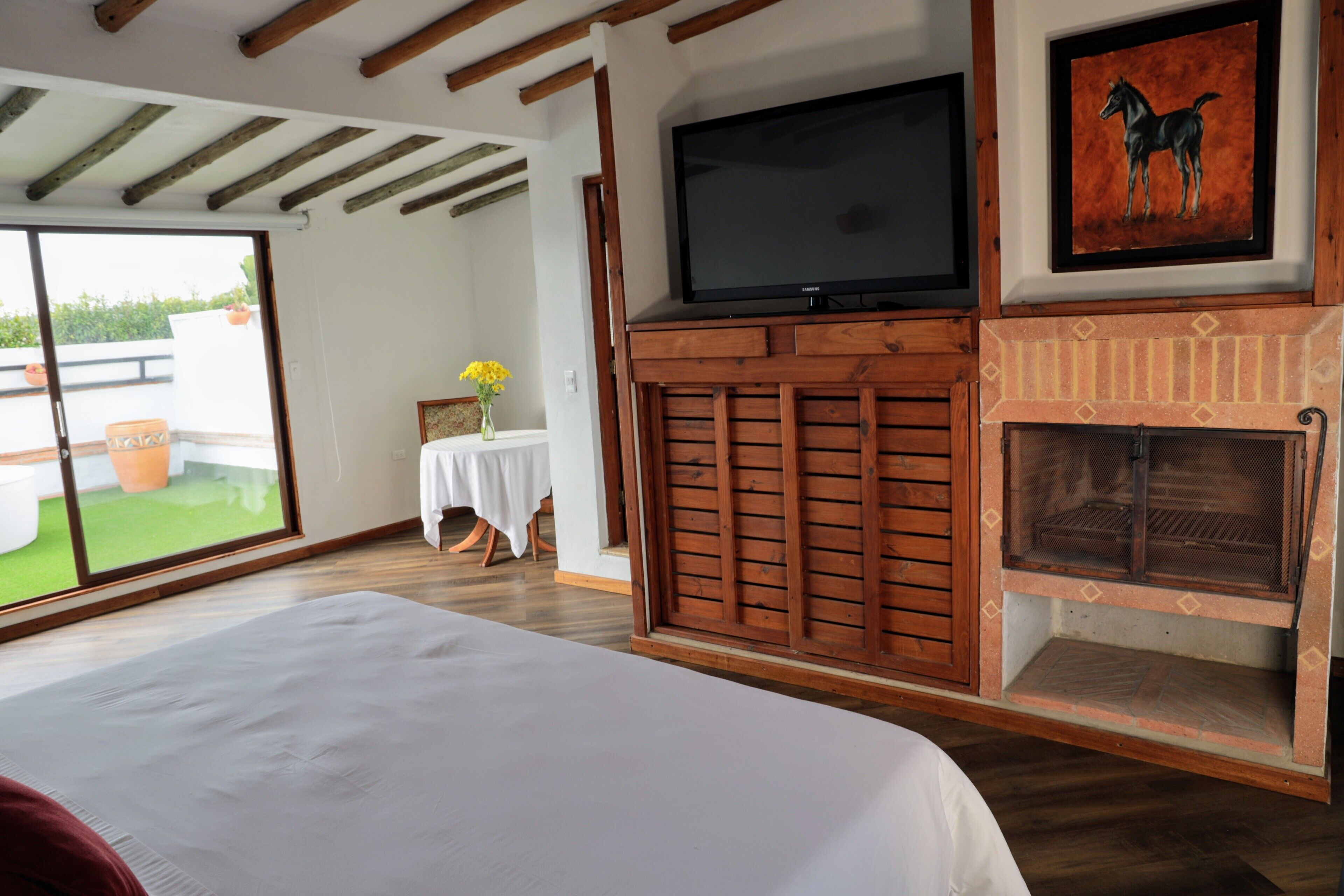 Een slaapkamer met een groot bed, een televisie, een open haard en een schuifdeur naar een buitengebied.