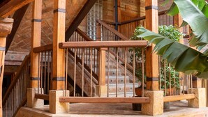A wooden staircase with a railing, surrounded by brick walls and wooden beams. - Hotel Plaza Mayor (Villa de Leyva)