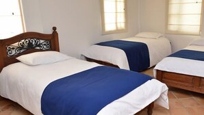 A room with three single beds, each with a wooden headboard and white bedding. - Hotel Campestre Bachue (Villa de Leyva)