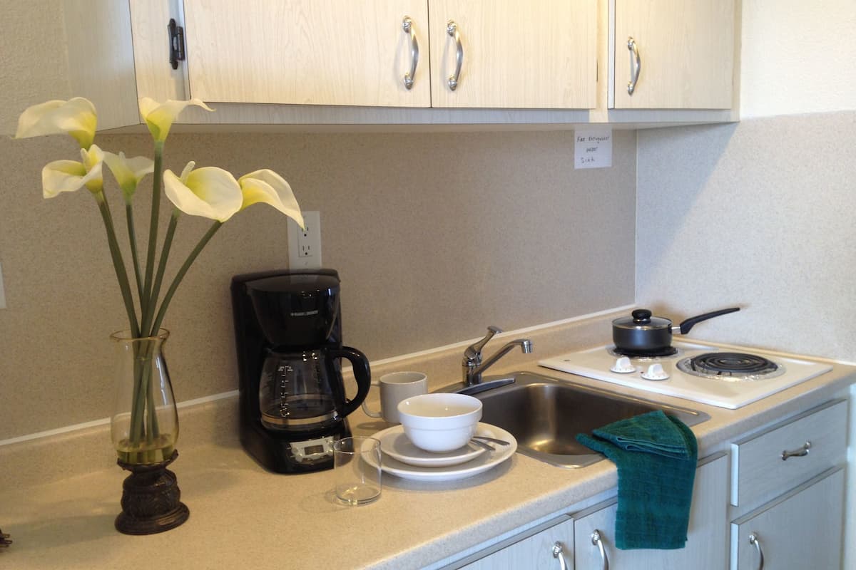 A kitchen with a coffee maker, a sink, and cabinets.
