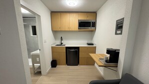 A compact kitchen with wooden cabinets, a microwave, a sink, and a coffee maker. - Inn Towne Motel (Hope)