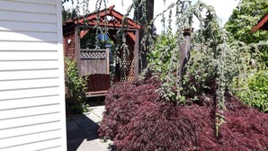 A garden with a wooden pergola, a wooden fence, and various shrubs. - Inn Towne Motel (Hope)