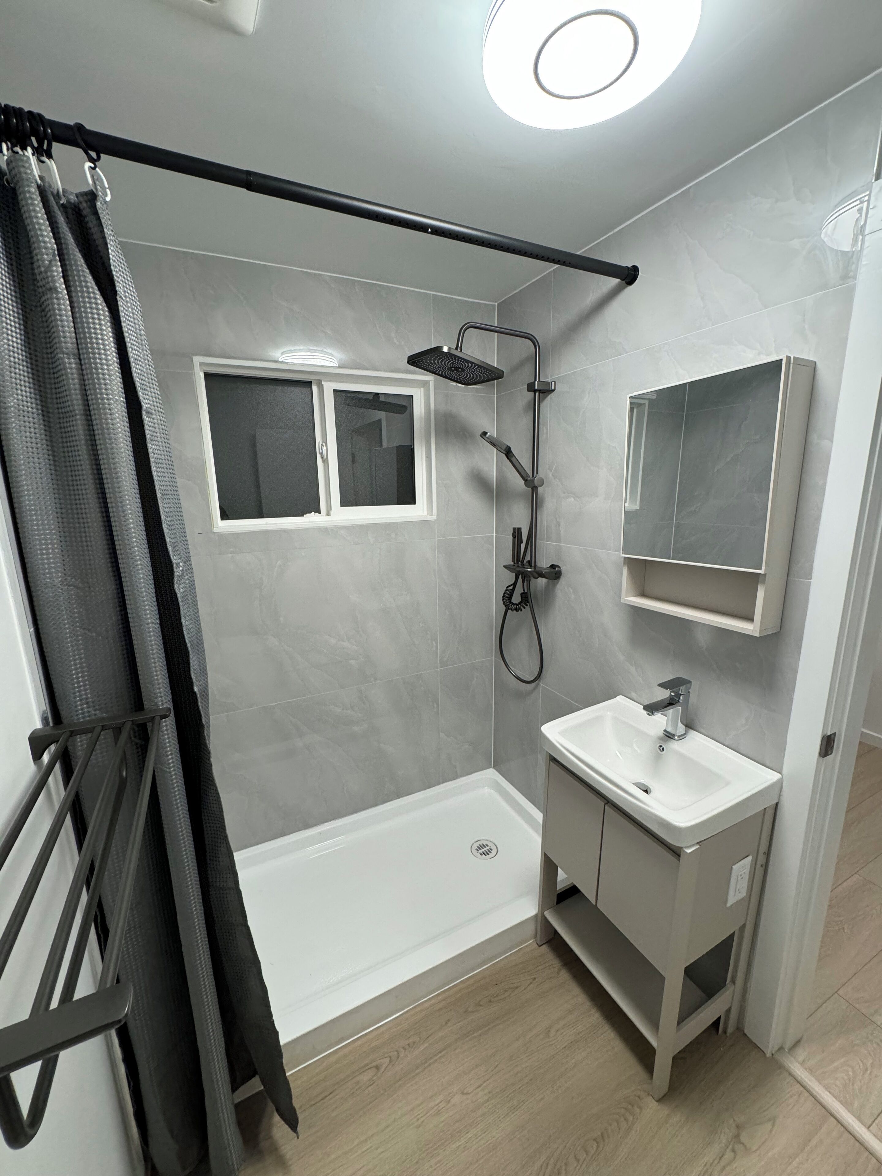 Un baño moderno con ducha, lavamanos y ventana.