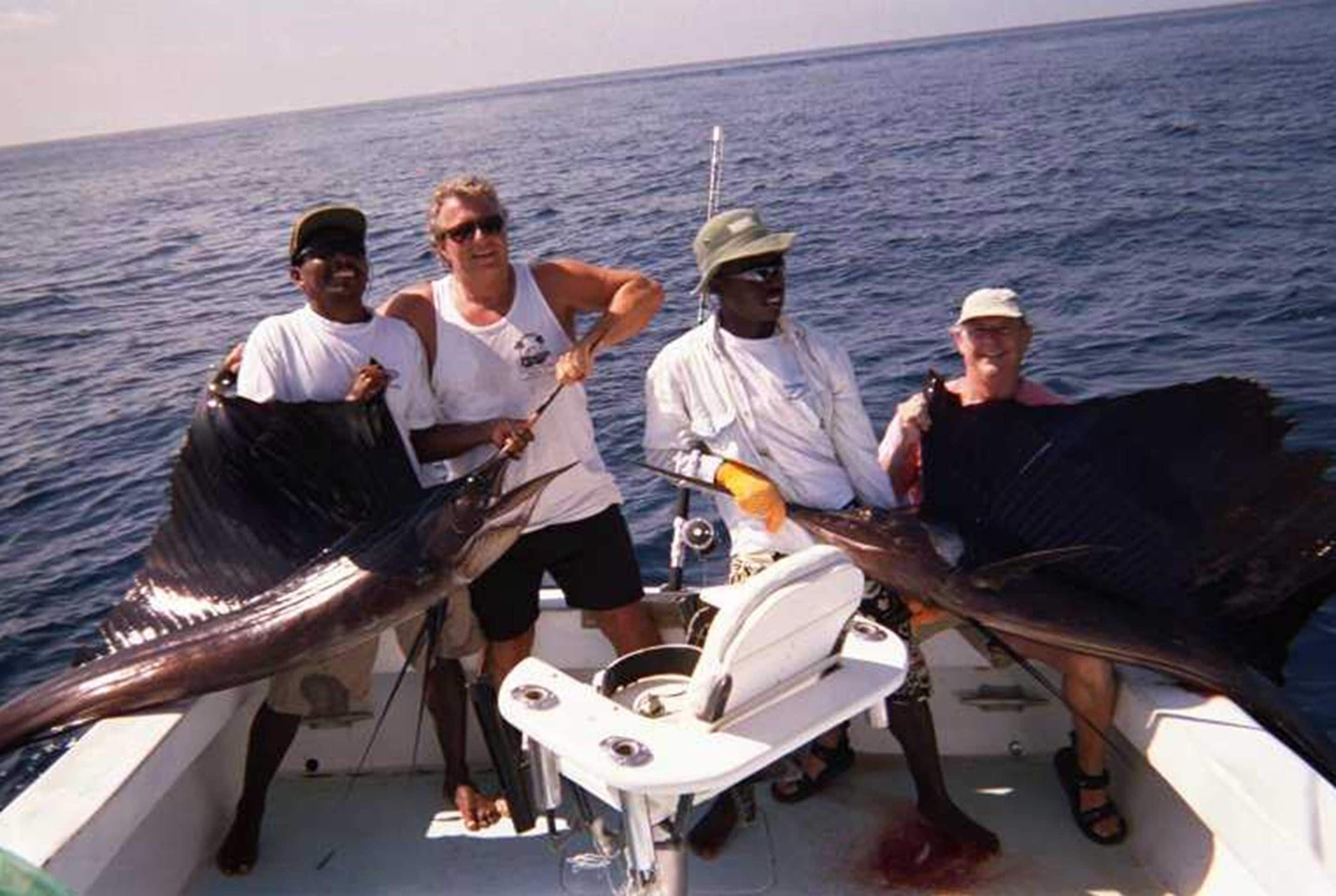 Un bote con cuatro personas sosteniendo peces grandes.