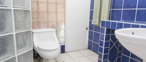 A bathroom with a toilet, sink, and tiled walls.