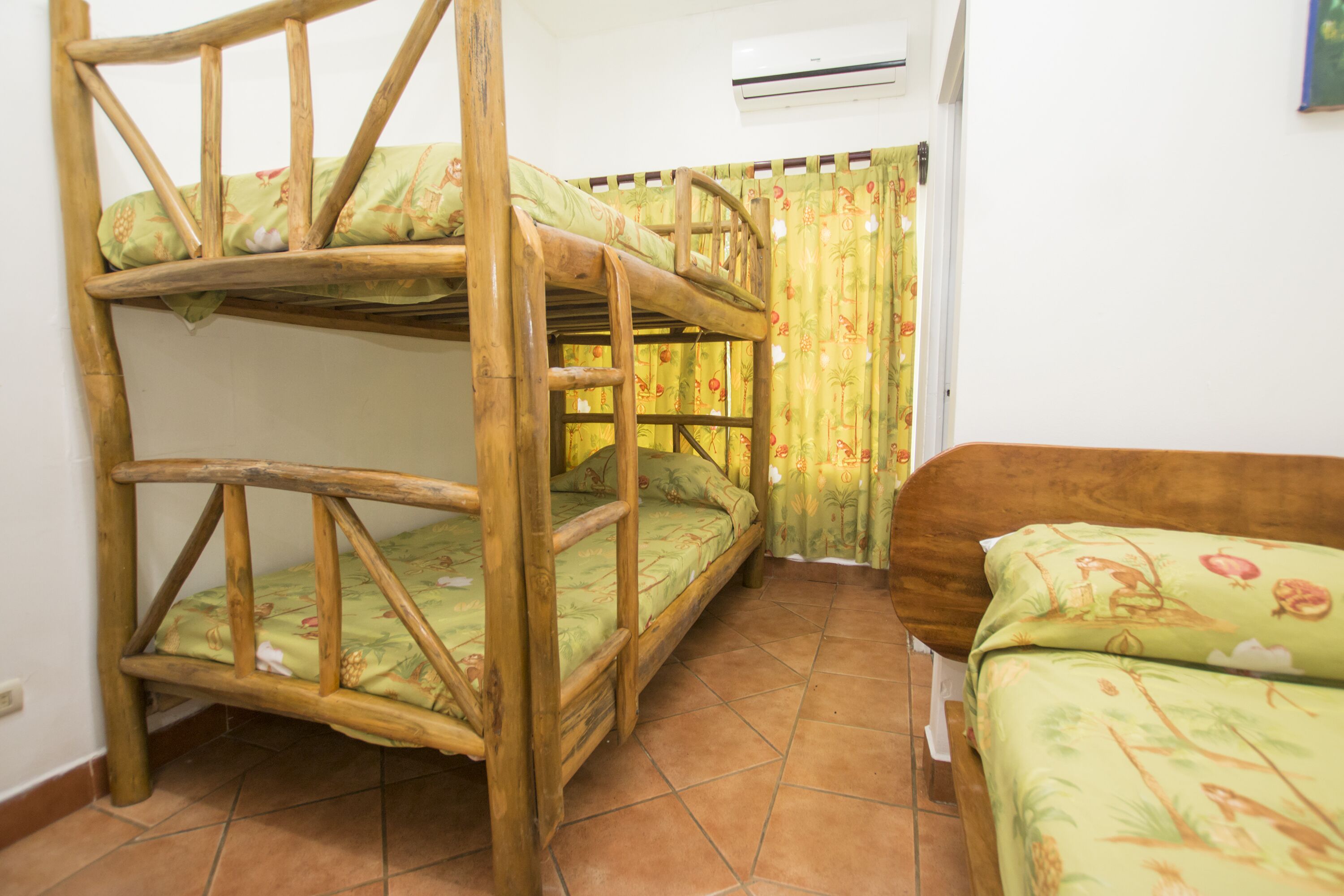 A room with two bunk beds and a single bed, all with floral bedding.