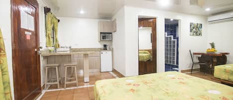 A compact hotel room with a bed, kitchenette, and a small dining area.