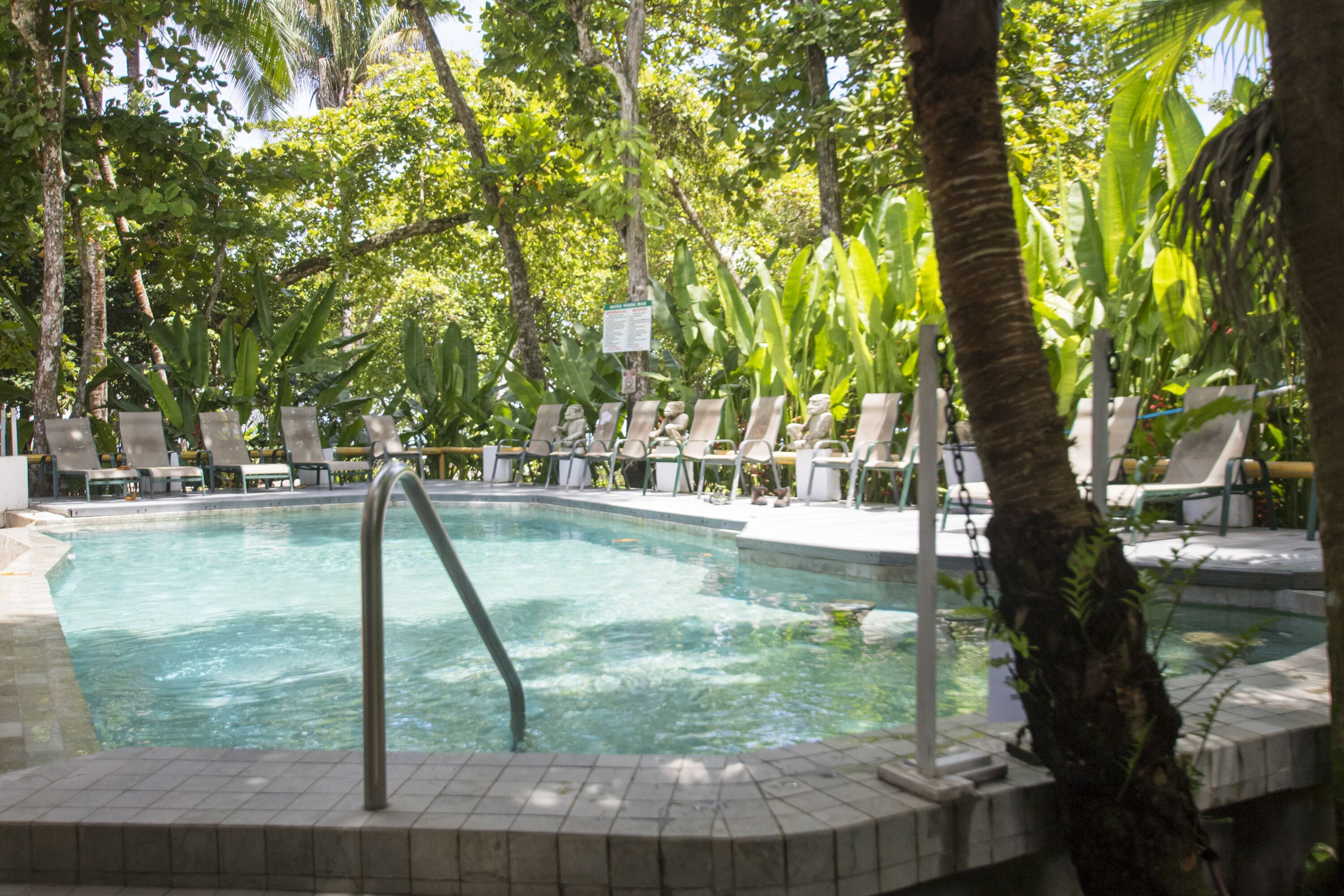 A pool area with lounge chairs and a signboard.