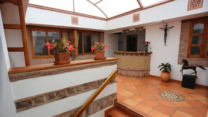 A spacious interior with a staircase, potted plants, and a tiled floor. - Hospedería Villa de Los Saenz (Villa de Leyva)