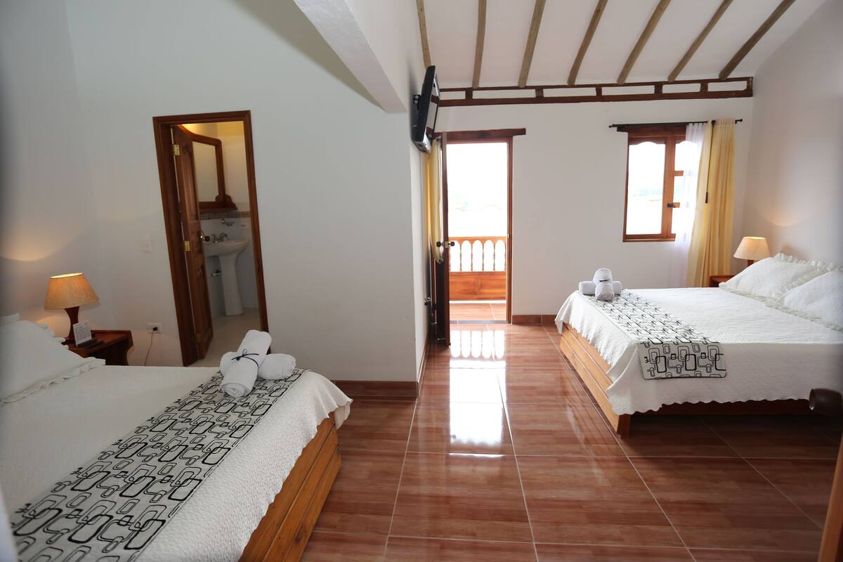 Habitación de hotel con dos camas, baño y balcón.