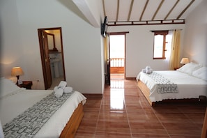 Een hotelkamer met twee bedden, een badkamer en een balkon.