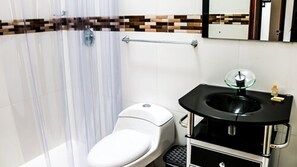 Een badkamer met toilet, glazen wastafel en douchegordijn.