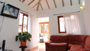 A spacious living room with a high ceiling, wooden beams, a large window, and a red sofa. - Hospedería Villa de Los Saenz (Villa de Leyva)