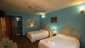 A hotel room with two beds, a ceiling fan, a mirror, a nightstand with a lamp, and a door leading to a bathroom. - Francis Arlene - Adults Only (Isla Mujeres)