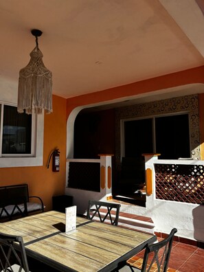 A dining area with a wooden table and chairs, a hanging light fixture, and a fire extinguisher on the wall. - Francis Arlene - Adults Only (Isla Mujeres)