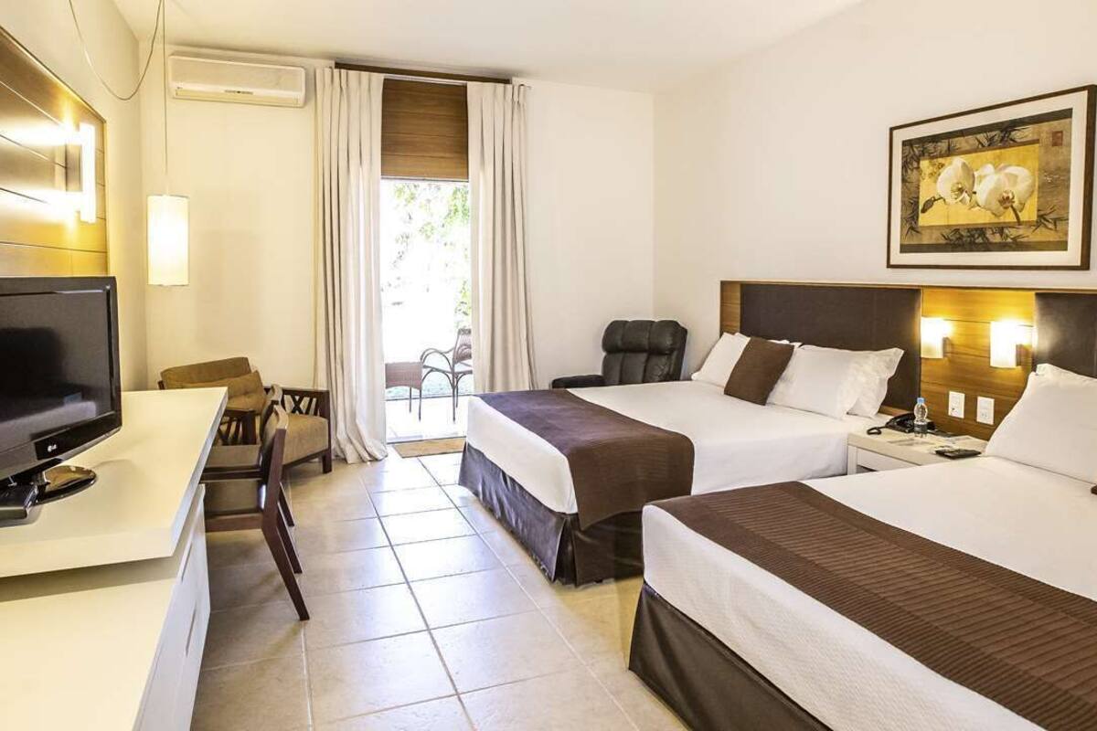 A hotel room with two beds, a desk with a television, and a painting on the wall.