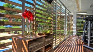 Habitación con piso de madera, caminadora y un amplio ventanal con vistas al verdor.