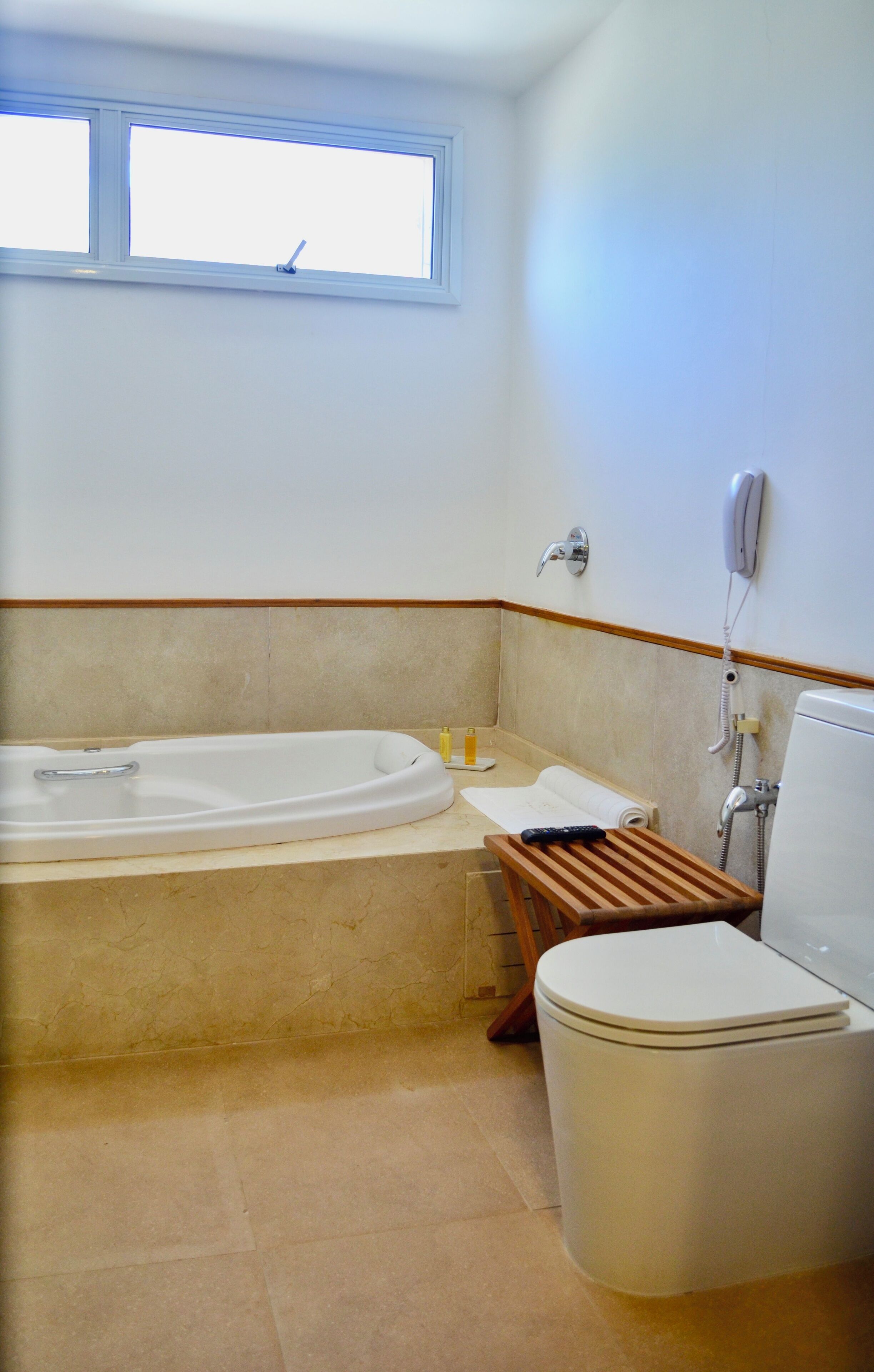 A bathroom with a bathtub, toilet, and a window.