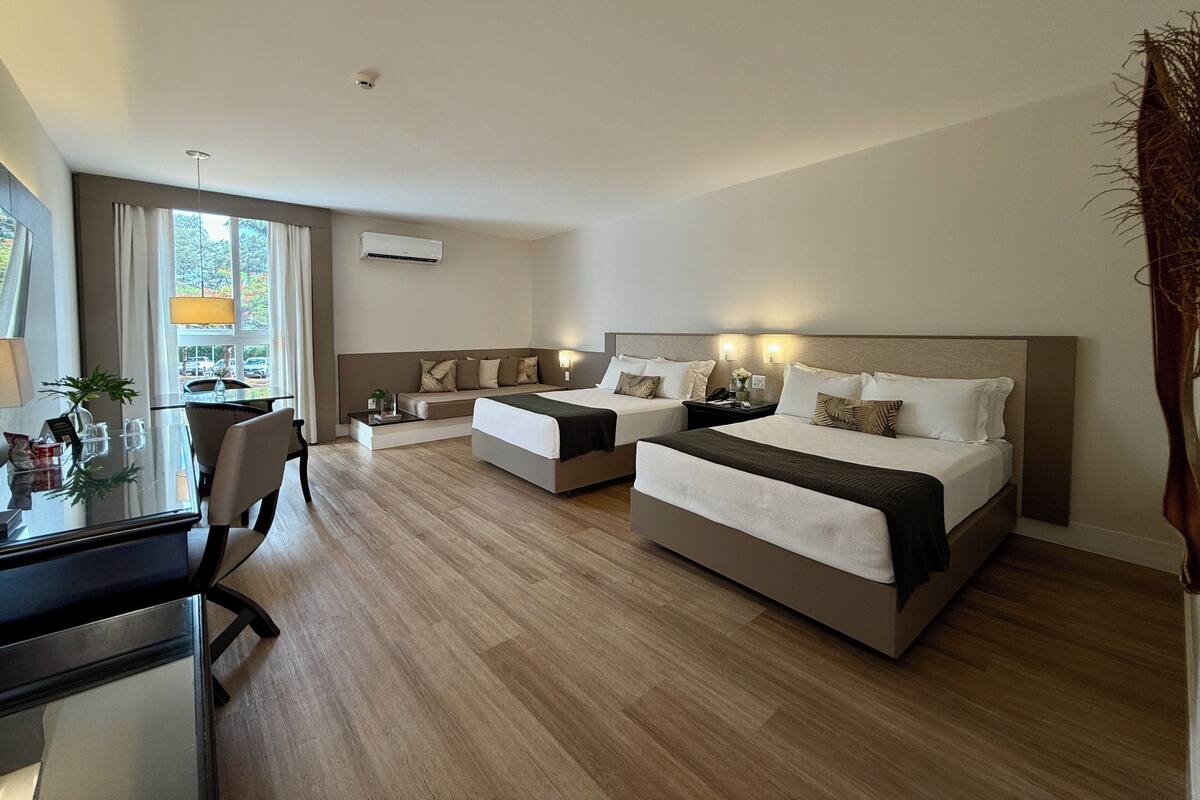 A hotel room with two beds, a desk, and a chair.