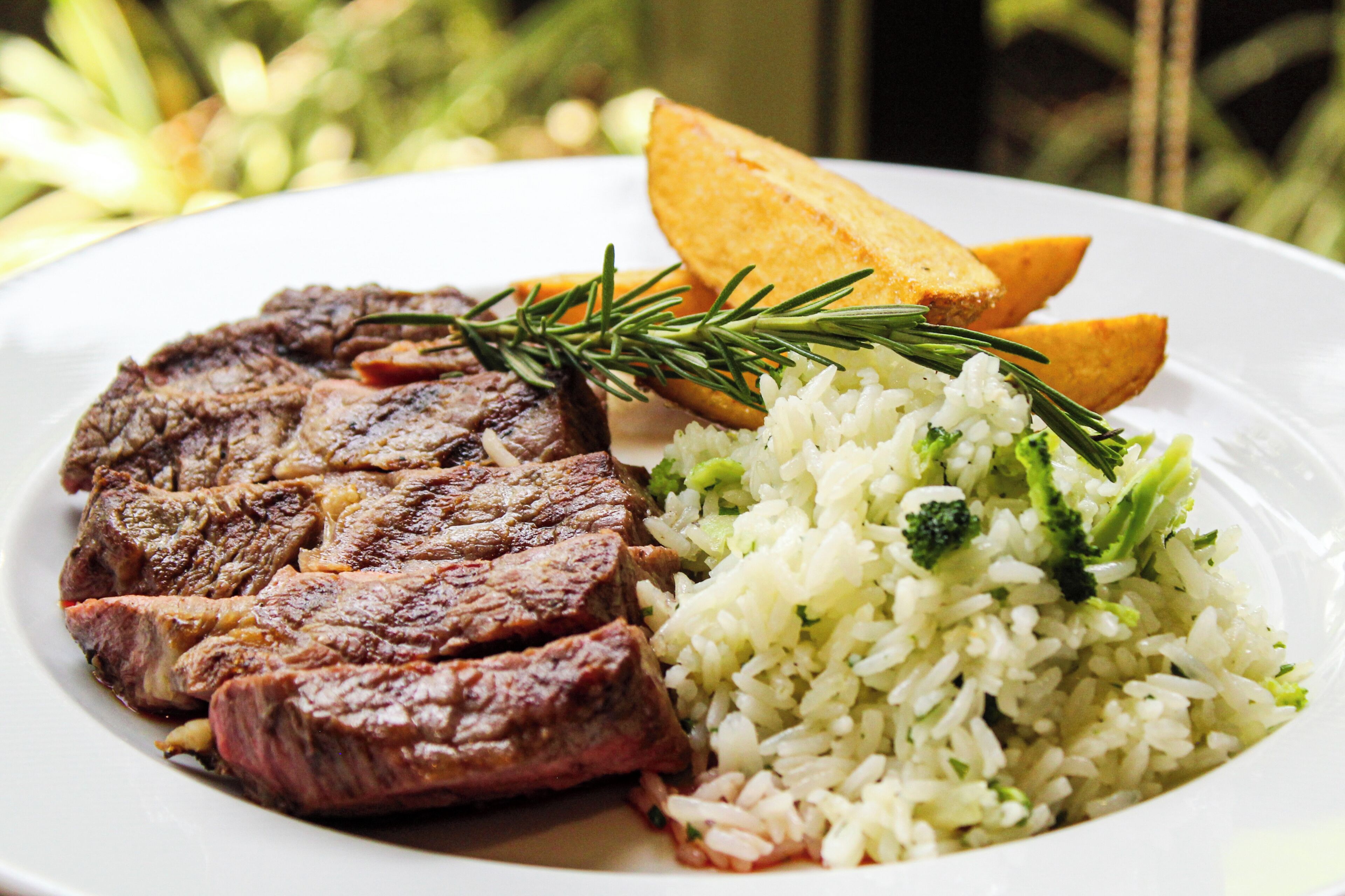 Um prato com bife, arroz e batatas assadas.