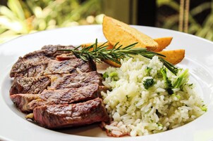 Um prato com bife, arroz e batatas assadas.