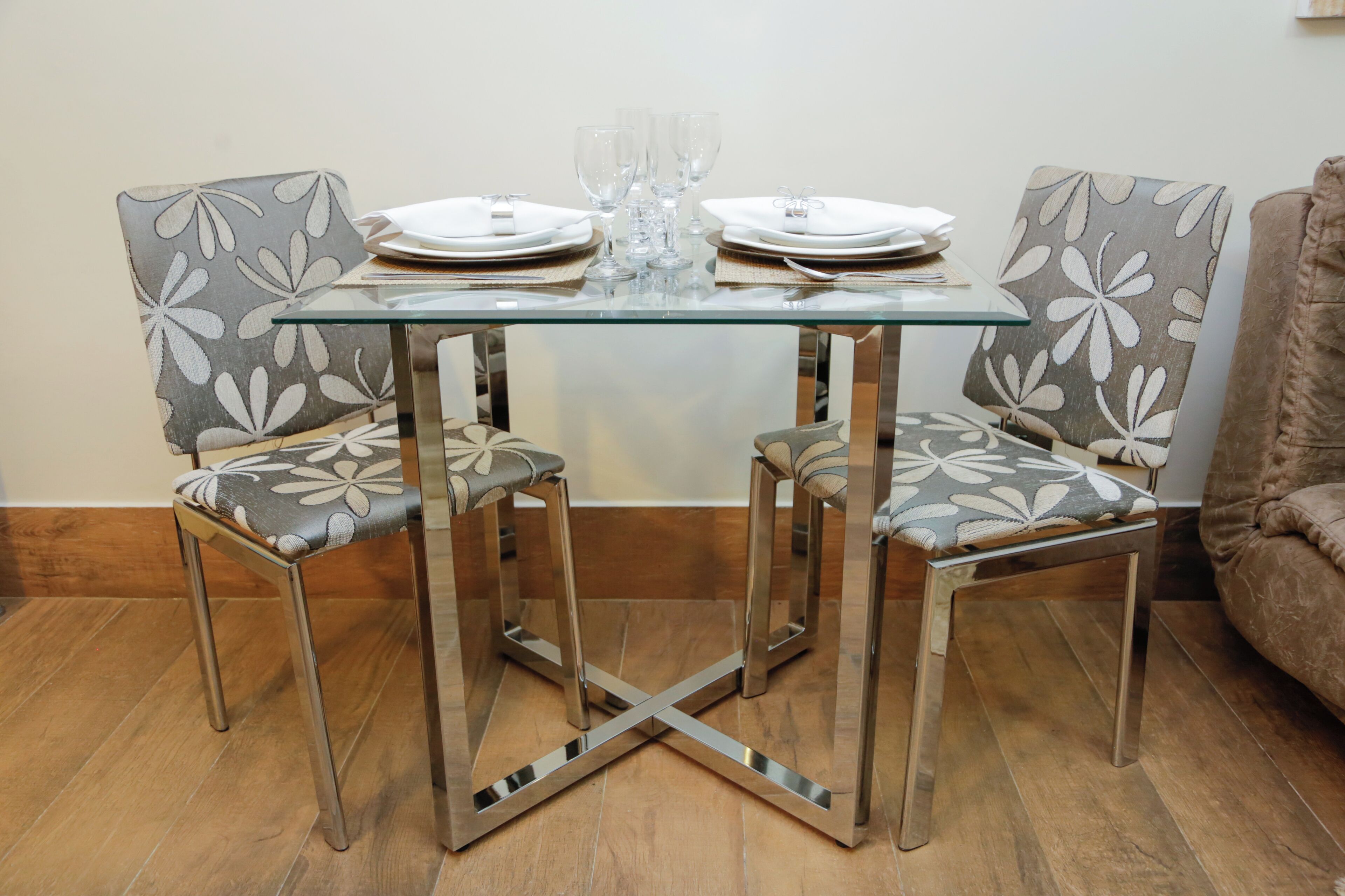 Una mesa de comedor con sillas, platos y vasos.