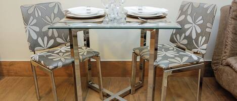 Una mesa de comedor con sillas, platos y vasos.
