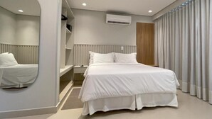 Un dormitorio moderno con una cama grande, una mesita de noche, un espejo y un equipo de aire acondicionado integrado.