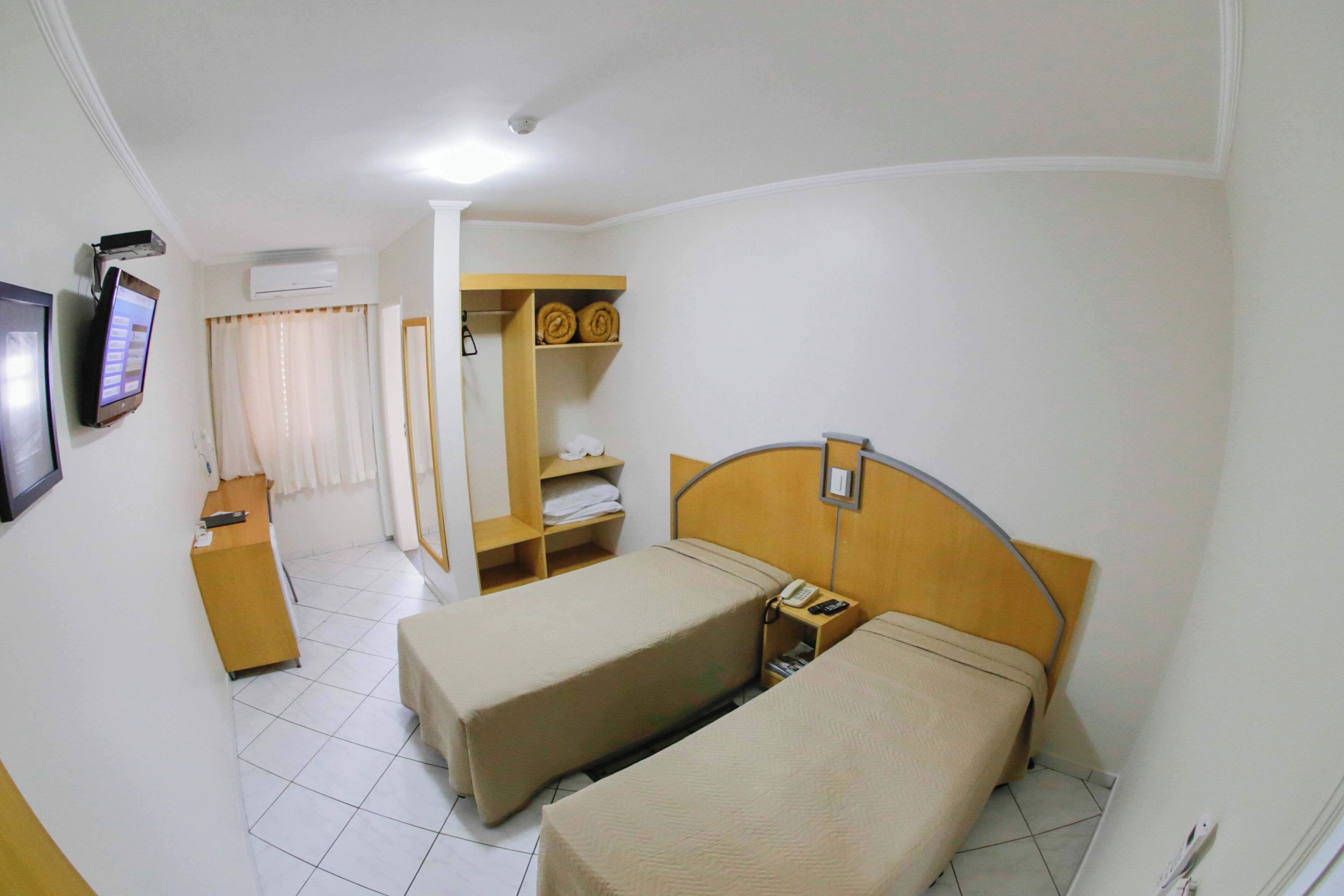 Una habitación de hotel con dos camas, un escritorio, un armario y un televisor.