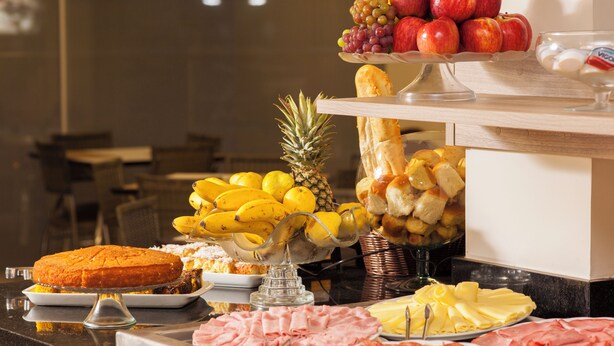 Un bufé con diversos alimentos, incluyendo frutas, pan y carnes.